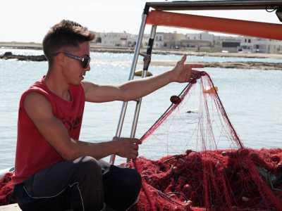 Il giovane Dino al lavoro con le reti da pesca